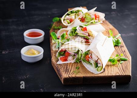 Frische Tortilla-Wraps mit Huhn und frischem Gemüse auf Holzbrett. Hühnerburrito. Mexikanische Küche. Gesundes Lebensmittelkonzept. Mexikanische Küche. Stockfoto