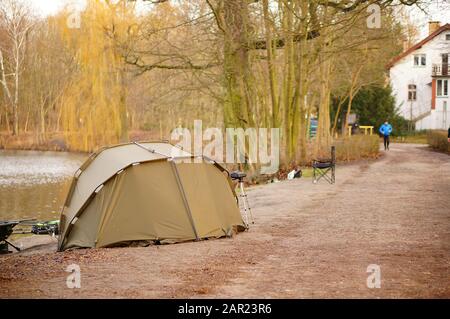 Posen, POLEN - 12. Januar 2020: Kleines Zelt und Angelausrüstung an einem See neben einem Fußweg im Wald von Debiec. Stockfoto