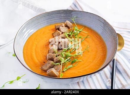 Kürbissuppe in einer Schüssel serviert mit Croutons und Erbsensprossen. Vegane Diätsuppe. Vegetarisches Essen. Stockfoto