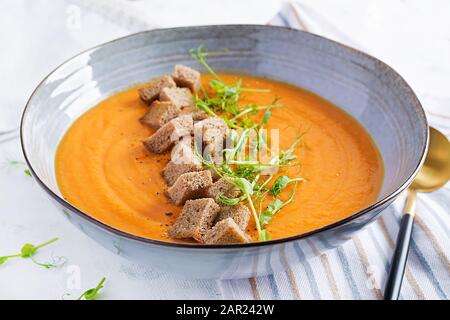 Kürbissuppe in einer Schüssel serviert mit Croutons und Erbsensprossen. Vegane Diätsuppe. Vegetarisches Essen. Stockfoto