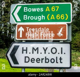 Drei Richtungsschilder für Bowes, A67, Brough, A66, Teesdale High Force und H.M.Y.O.I. Deerbolt. Das Hotel befindet sich in Teesdale, County Durham, England, Großbritannien. Stockfoto