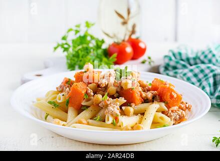 Italienische Pasta, Penne mit Hackfleisch, Kichererbsen und Kürbis. Gesunde Ernährung. Pasta mit Pinzettenverzat. Stockfoto