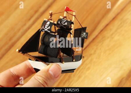 High-Angle-Aufnahme einer Person, die mit einem Piraten spielt Schiff Spielzeug über einer hölzernen Oberfläche Stockfoto