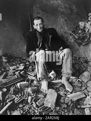 Französischer Gefangener, der in Trümmern sitzt und auf Ambulanz wartet, um ihn zur Zeit der Befreiung durch die US-Armee, Nordhausen, Deutschland, ins Krankenhaus im deutschen Slave-Arbeitslager zu bringen, Foto von Roberts für das US Army Signal Corps, April 1945 Stockfoto