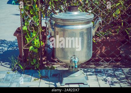Metallsamovar auf grünem Hintergrund. Alte schäbige Eisen samovar .Vintage Metall Kupfertee. Samovar-Seitenansicht. Retro-Ruß-Grunge Tee Samovar wurde für verwendet Stockfoto