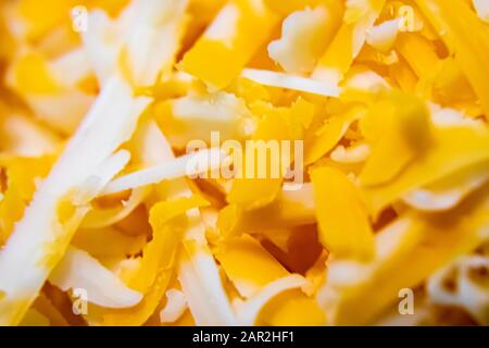Nahaufnahme des zerkleinerten Käses aus Bauernmarmor mit Cheddar-Käse, der die Details und Farben der Speisen zeigt. Stockfoto