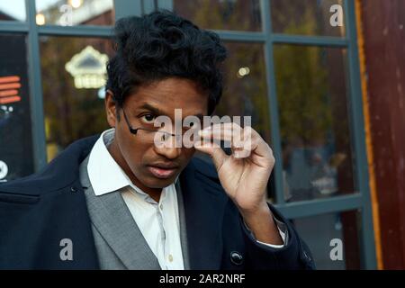 Hübscher junger gemischter Rasse Mensch über seine Brille. Stockfoto