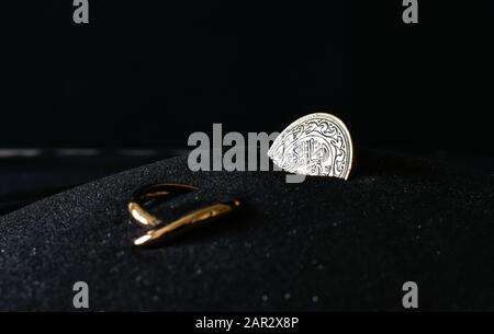 Goldring und arabische Münze auf dem schwarzen Sand Stockfoto