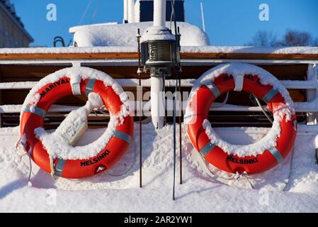 Helsinki, Finnland - 6. Februar 2019: Rote Lebensbojen am Heck eines verschneiten Schiffes in Kaupatori Helsinki, Finnland. Am kalten Wintertag. Stockfoto