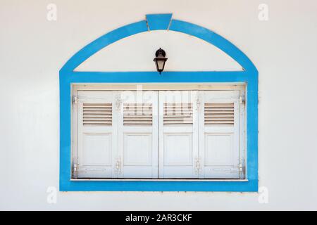 Fensterläden. Zerrissene Wand mit geschlossenen Blenden am Fenster. Außenansicht alter Fensterläden und Wände. Hintergrund der Wand mit weißen Vintage-Blenden. Altes Vintage-Retro-Äußeres des Gebäudes Stockfoto