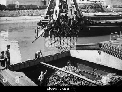 Holländischer Ruhm auf der Rheinschifffahrt, Reportage aus dem Schleppboot Damco 9: Schweiz. Abladen von Schrott im Hafen Basel-Kleinhüningen Datum: 1. April 1955 Standort: Basel, Schweiz Schlagwörter: Binnenschiffe, Hafenarbeiter, Häfen, Kräne, Be- und Entladen, Skipper, Schrott Stockfoto