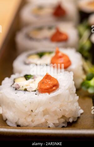 Schneiden Sie Sushi-Rollen mit Blumen und radischen Wurzeln, die mit Krabbenfleisch und Thunfisch gefüllt sind Stockfoto