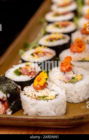 Schneiden Sie Sushi-Rollen mit Blumen und radischen Wurzeln, die mit Krabbenfleisch und Thunfisch gefüllt sind Stockfoto