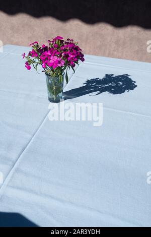 Leerer Tisch mit Blumen in Vase mit blauem Tischtuch. Stockfoto