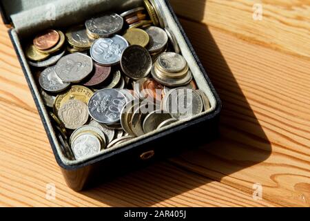 High-Angle-Aufnahme der Box voller Münzen auf einem Holzoberfläche Stockfoto