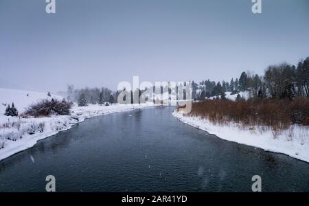 Schneefall auf einem Abschnitt der Clark Fork des Columbia River an einem kalten Wintertag, bei Bearmouthh, westlich von Drummond, Montana, im Granite County. Stockfoto