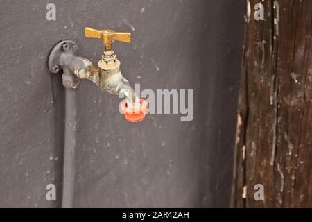 High-Angle-Aufnahme von einem Wasserhahn auf einer schwarzen Wand Stockfoto