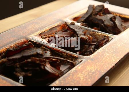 Biltong (getrocknetes Fleisch) auf einem Holzbrett, das ist ein traditioneller Imbiss Stockfoto