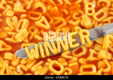 Spaghetti-Rechtschreibsieger mit zufälligen Buchstaben im Hintergrund der Tomatensauce Stockfoto