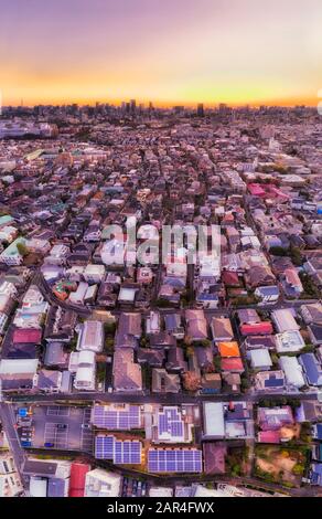 Endlose Vororte und Bezirke der Stadt Tokio von lokalen Häusern in Shimo-Kitazawa bis hin zu entfernten Toky CBD Wolkenkratzern bei Sonnenaufgang unter orangefarbenem Himmel. Stockfoto