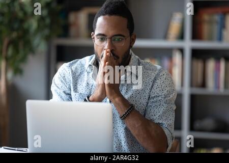 Schockierter afrikanischer Geschäftsleute fühlt sich frustriert, wenn er einen Laptop-Bildschirm betrachtet Stockfoto