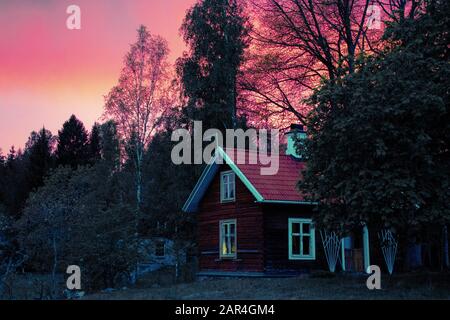 Traditionelle schwedische Blockhütte und Dämmerung mit dramatischem roten Himmel. Stockfoto