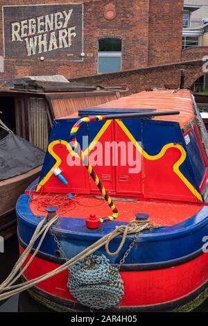 BIRMINGHAM, Großbritannien - 28. MAI 2019: Hell gestrichenes Schmalboot auf dem Kanal am Brindley Place vor dem viktorianischen Regency Wharf Stockfoto