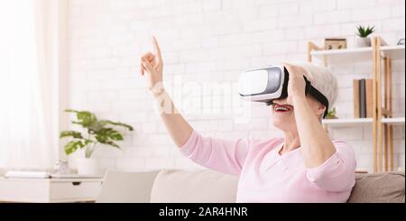 Fröhliche Seniorin genießt zu Hause moderne Technologien Stockfoto