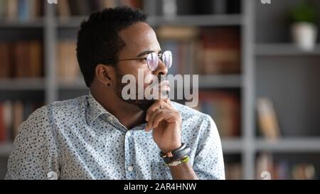 Nachdenklicher, zweifelhafter afrikanischer Geschäftsmann, der wegschaut, verlor an Gedanken Stockfoto