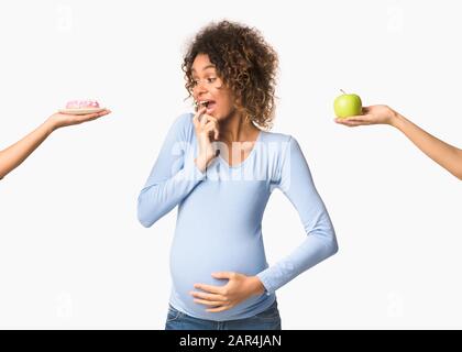 Afro schwangere Frau, die zwischen süß und Obst wählt Stockfoto