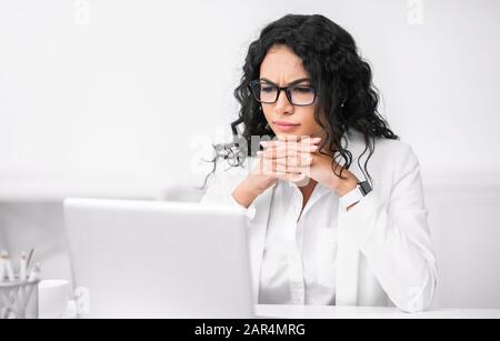 Seriöse hispanische Managerin, die ihren PC verwendet Stockfoto