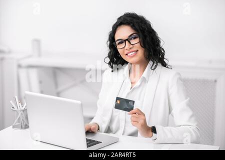 Lächelndes lateinisches Mädchen, das mit dem Computer Spenden macht Stockfoto