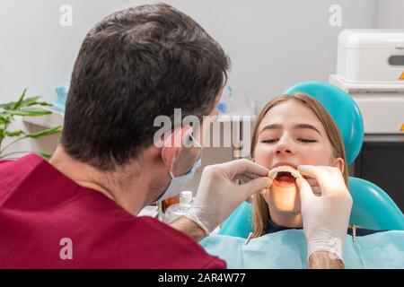 Der Zahnarzt legt seine Zähne auf seinen Patienten Stockfoto