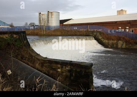 Weir am Fluss irwell mit Industriegebäuden und Silos im Hintergrund in Bury lancashire UK Stockfoto