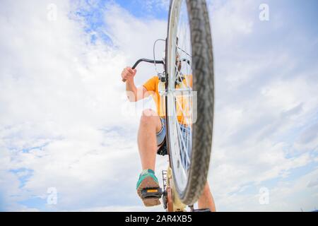 Mann bärtiger Flusspferd reitet Fahrrad unten Blick Himmel Hintergrund. Ratschläge für die Fahrradmechaniker. Die Räder in einwandfreien Zustand halten. Einkaufsführer für Radräder. Überprüfen Sie den Fahrrad-Service, um sicher zu gehen. Stockfoto