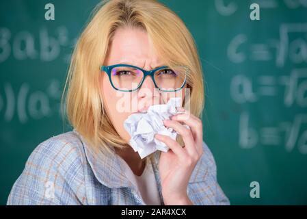 Hungrig nach Wissen. Lehrerin bereit, ihre Unterlagen zu essen. Lehrer isst Papier absorbiert Informationen. Wissensdurst. Frauenlehrerin isst zerknitterten Papier-Schwarzen-Board-Hintergrund. Stockfoto