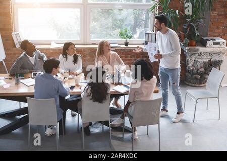 Das junge Business-Team hat Treffen und hört sich den Marketingbericht an Stockfoto