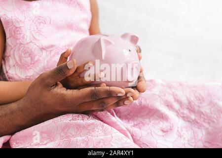 Nahaufnahme des schwarzen Vaters und der Tochter, die eine piggy Bank hält Stockfoto