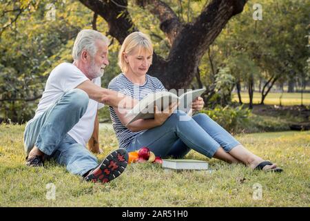 Älteres Paar liest am Morgen im Park zusammen. Konzept der Paare ältere gut gesund und stark. Großvater und Großmutter lesen einen Buh Stockfoto