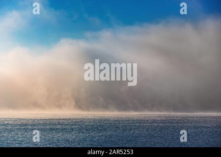 Meer Sonnenaufgang und nebliger Morgen. Nebel über blauen Wellen Wasser, Luftbild. Stockfoto