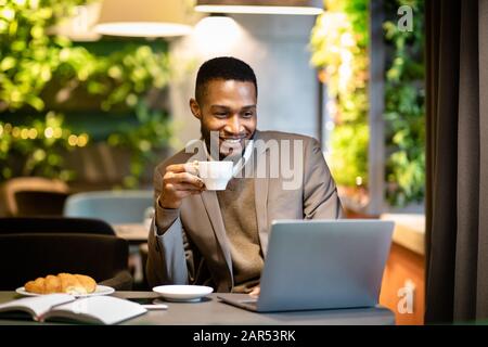 Schwarzer Kerl, der eine Tasse Kaffee im Büro hält Stockfoto