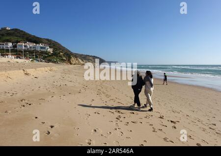 Salema, Portugal 29. Dezember 2019: Menschen, die am Strand in der Küstenstadt Salema in Portugal spazieren; Stockfoto