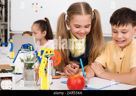 Intelligente Schüler, die an einem neuen Robotikprojekt arbeiten, machen sich Notizen Stockfoto