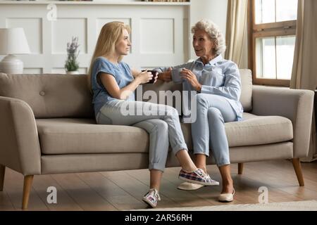 Lächelnde Mutter mittleren Alters im Gespräch mit erwachsener Tochter. Stockfoto