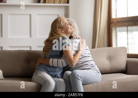 Zwei Generationen liebende Familie, die sich auf der Couch umarmte. Stockfoto