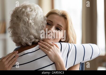 Frau mittleren Alters, die lächelnde Erwachsene attraktive Tochter umarmte. Stockfoto