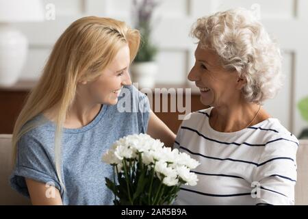 Junge lächelnde blonde Erwachsene Tochter gratuliert glücklicher Mutter. Stockfoto