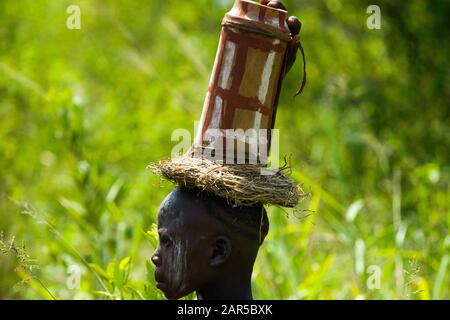 Mursi-Junge, der einen Krug auf dem Kopf trägt. Die Mursi (oder Murzu) sind ein subsaharanisch-afrikanischer nomadischer Viehhirtenstamm, der im Omo-Tal in Südwes beheimatet ist Stockfoto