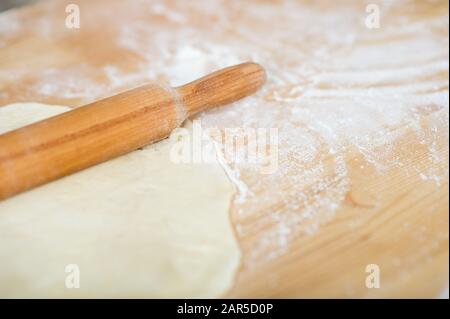 Rollstift und Teig liegen auf einem mit Mehl bestreuten Tisch Stockfoto