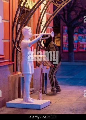 Moskau, Russland - 17. Januar 2020: Eingang zum Straßencafé in der Innenstadt am Abend. Der Besucher der Frau durchläuft die Eingangstür. Vorhalle mit Licht erhellt Stockfoto